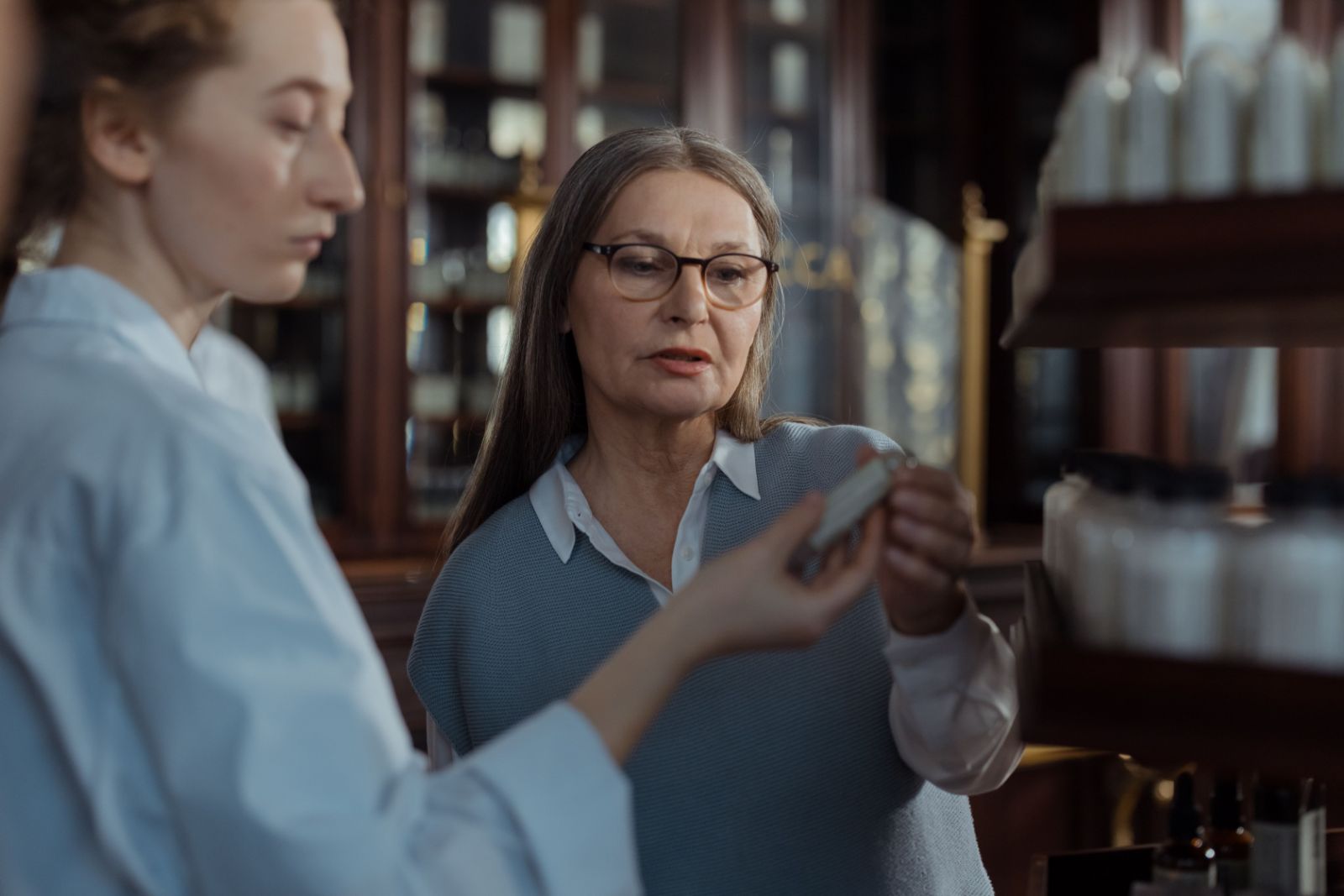 Farmacéutica explicando un tratamiento a una paciente en el mostrador